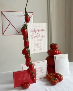 there are tomatoes on the table with cards and envelopes