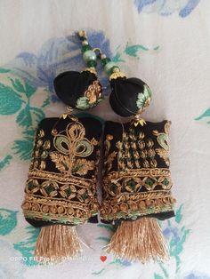 two black and gold purses with tassels hanging from them on a bed