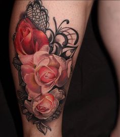 a close up of a person's leg with tattoos on it and two roses