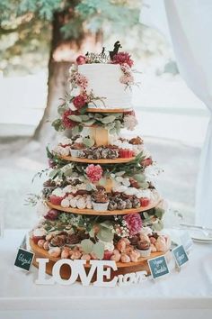 a tiered cake sitting on top of a table next to a sign that says love