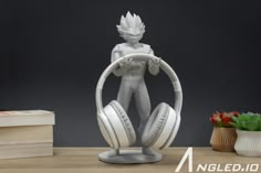 a white statue with headphones on top of a wooden table next to some books