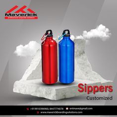 two red and blue water bottles sitting next to each other on top of a rock