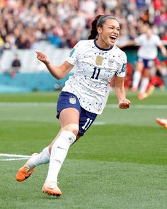 a female soccer player is running on the field with her mouth open and eyes closed