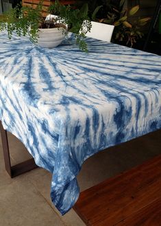 a blue and white table cloth on top of a wooden table with a potted plant