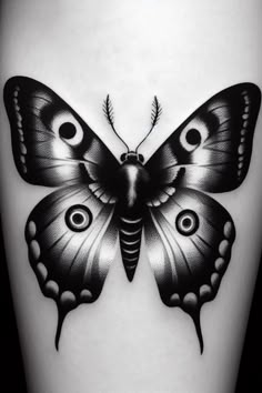 a black and white butterfly tattoo on the thigh