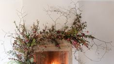 the fireplace is decorated with flowers and greenery on it's mantle, along with candles