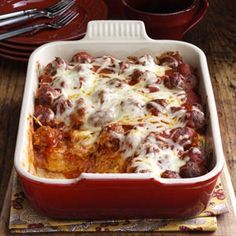 a casserole dish with meat and cheese in it sitting on a wooden table