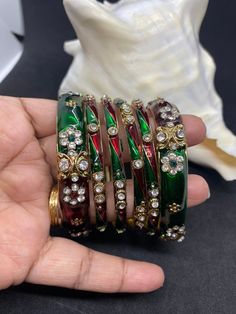 This design of bangles are called meena Kiri bangles. This bangles is green and red with stone works. This set comes in set of 6 bangles. Size 2.8 and inner length is 6.4cm Red Bollywood Bracelet Gift, Multicolor Cutdana Bracelets As Gifts, Traditional Jeweled Bangle As Gift, Red Cutdana Bracelets For Diwali, Multicolor Cutdana Bangle Bracelet, Green Bracelets For Puja And Festivals, Green Jeweled Bangle Bracelets, Festive Green Bracelets For Celebration, Red Bollywood Bangle With Stone Work