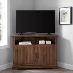 a flat screen tv sitting on top of a wooden entertainment center next to a window