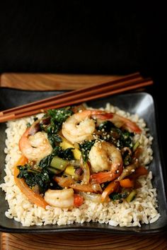 shrimp and vegetable stir fry on rice with chopsticks