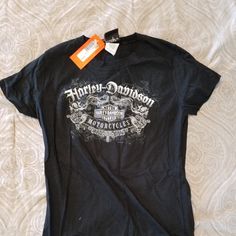 a black t - shirt with an orange tag on the front that says mountain country motorcycle