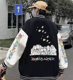 a person walking down the street wearing a jacket with elephants on it and birds flying over them