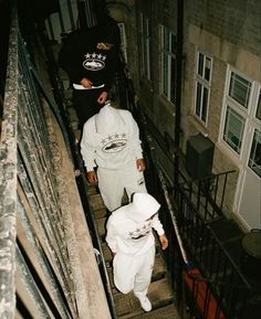 two people in white outfits walking down some stairs