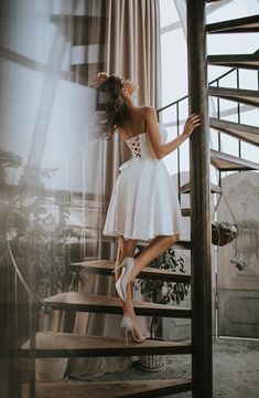 a woman in a white dress standing on some stairs