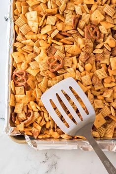 cheetos and pretzels in a casserole dish with a spatula