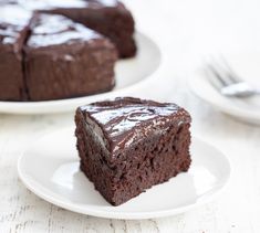 a piece of chocolate cake on a white plate with a fork next to the slice