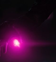 a person holding a pink object in their hand with the light shining on it's side