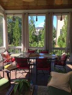 a covered porch with lots of furniture and windows looking out onto the trees outside on a sunny day