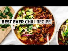 two bowls filled with chili and veggies on top of a table next to a cutting