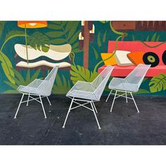 three white chairs sitting in front of a colorful wall with plants and animals on it