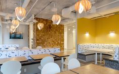 an empty restaurant with yellow walls and white chairs, wooden tables and benches in the center