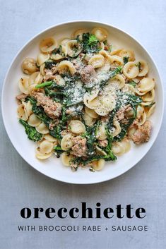 a white bowl filled with pasta and meat covered in sauce on top of a table