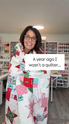 a woman in glasses holding up a quilt