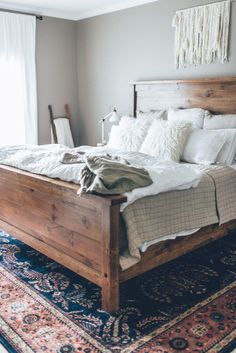 a bed with white linens and pillows in a bedroom next to a large rug