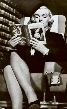 a black and white photo of a woman reading a book