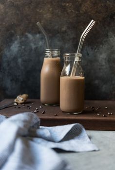 two jars filled with chocolate milkshakes on top of a table