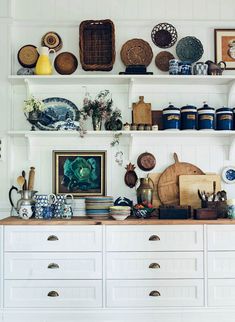 a kitchen with white cabinets and shelves filled with dishes