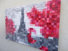 a piece of art made out of paper with red, grey and white squares on it