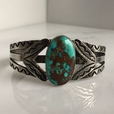 "Details: Lovely Native American Sand Cast Turquoise and Silver Bracelet. The turquoise is a deep blue with silver veins, and measures 1\" x 3/4\", and the face of the bracelet measures 1 3/4\" high. This piece has a nice weight to it. Please ask all necessary questions prior to placing an order. Measurements: The bracelet is a cuff, and can be adjusted to fit small to medium wrists. The interior measures 2 1/2 across, and the interior measures 5 1/2 inches.. Condition: The overall all condition Classic Turquoise Adjustable Bracelet, Classic Adjustable Turquoise Cuff Bracelet, Turquoise Cuff Bracelet With Polished Finish, Oval Turquoise Collectible Bracelet, Southwestern Engraved Blue Cuff Bracelet, Adjustable Turquoise Cuff Bracelet With Polished Finish, Classic Turquoise Cuff Bracelet Gift, Adjustable Turquoise Polished Cuff Bracelet, Blue Turquoise Oval Bracelet