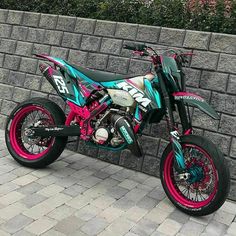 a colorful dirt bike parked next to a brick wall