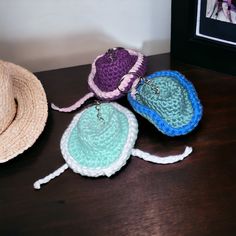 three crocheted hats sitting on top of a wooden table