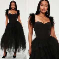 a woman wearing a black dress with feathers on it