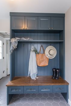 a bench with a hat, coat rack and boots on it in a room that has blue painted wood paneling