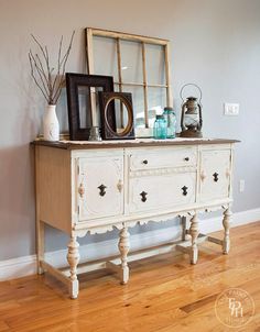 a white dresser with some pictures on top of it and an old mirror above it