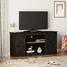 a flat screen tv sitting on top of a wooden entertainment center in a living room