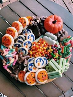 an assortment of cookies and candies arranged on a wooden table with a pumpkin in the center