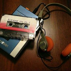 an audio cassette and headphones on top of a wooden table next to each other