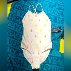 a white swimsuit with multicolored stars on it sitting on a blue blanket