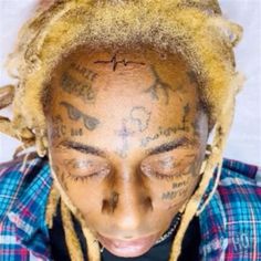 a man with yellow dreadlocks and tattoos on his face is looking at the camera