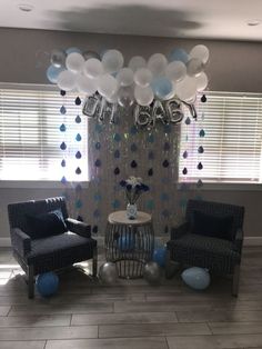 balloons and streamers are hanging from the ceiling in front of a party backdrop with chairs