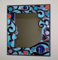 a mirror that is on the wall with a blue and orange design around it's edge