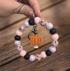 a person holding onto a keychain made out of beads and plastic pumpkins