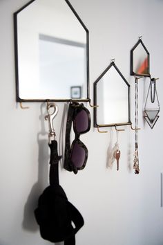 there is a mirror, sunglasses and other items hanging from the hooks on the wall