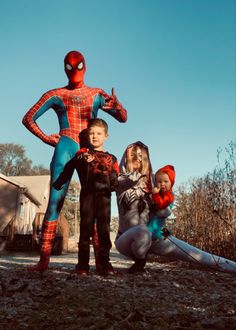 three children standing in front of a spider man statue