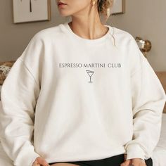 Wrap yourself in cozy comfort with our Espresso Martini Club sweater. Simple yet stylish, this sweater is perfect for casual outings or lounging at home. Whether you're a coffee lover or a cocktail enthusiast, this sweater is sure to become a favourite. Available in a range of sizes, treat yourself or surprise a friend with this delightful piece of wearable art Unisex Gildan 1800 heavy blend crewneck sweatshirt is pure comfort. These garments are made from 50% polyester and 50% cotton. This comb Graphic Print Crew Neck Top For Lounging, Crew Neck Winter Lounging Tops, Crew Neck Top For Winter Lounging, Crew Neck Tops For Lounging In Winter, Winter Lounging Tops With Crew Neck, Winter Lounging Crew Neck Tops, Relaxed Fit Graphic Print Top For Lounging, Trendy Long Sleeve Tops For Lounging, Trendy Cotton Sweatshirt For Lounging