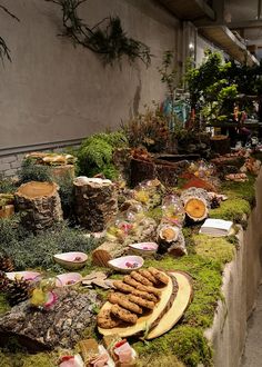 a table covered in lots of different types of food and plants next to a building